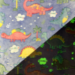 Wellness Fleece Glow In The Dark Dino stof met regenbogen, wolken en de tekst “Dinosoup”. Perfect voor stoere pyjama’s, dekens en kinderkamer