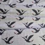 Tricot stof met draken zwarte draak met rode zadel op lichtgrijze achtergrond Makomastoffen Nederland